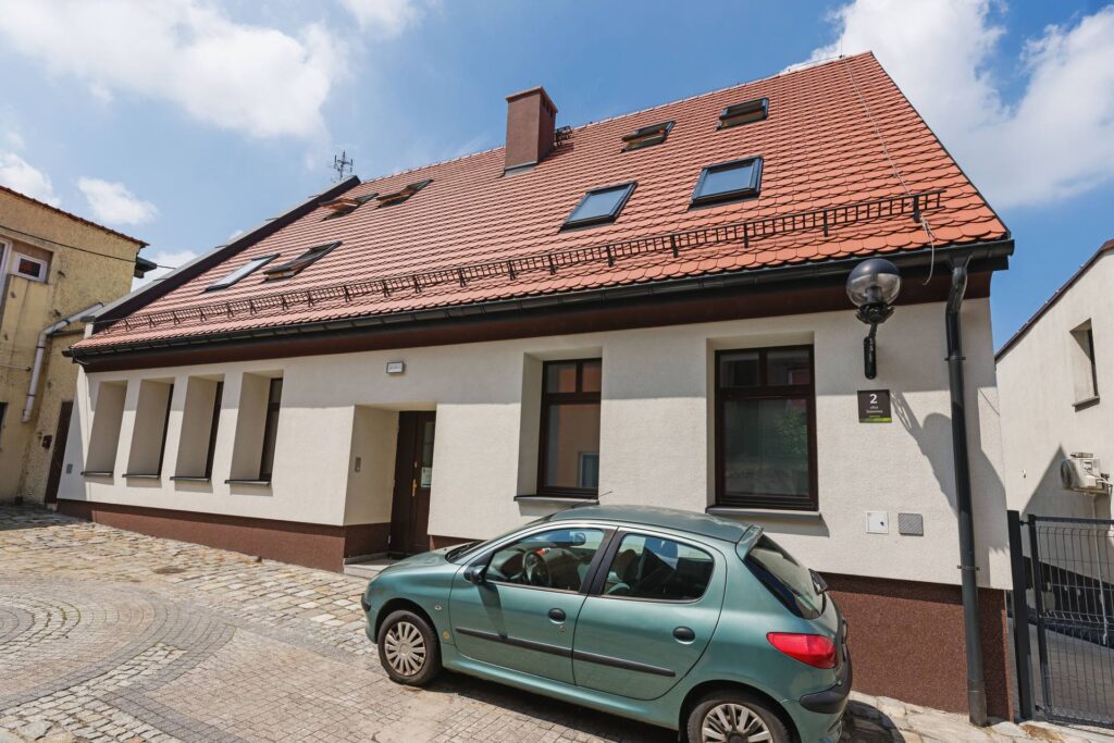 Budynek usługowo-mieszkalny przy ul. Stawowej w Mikołowie po wykonaniu elewacji metodą lekką mokrą: biały tynk, ciemnobrązowy cokół, dach z ceglastej dachówki