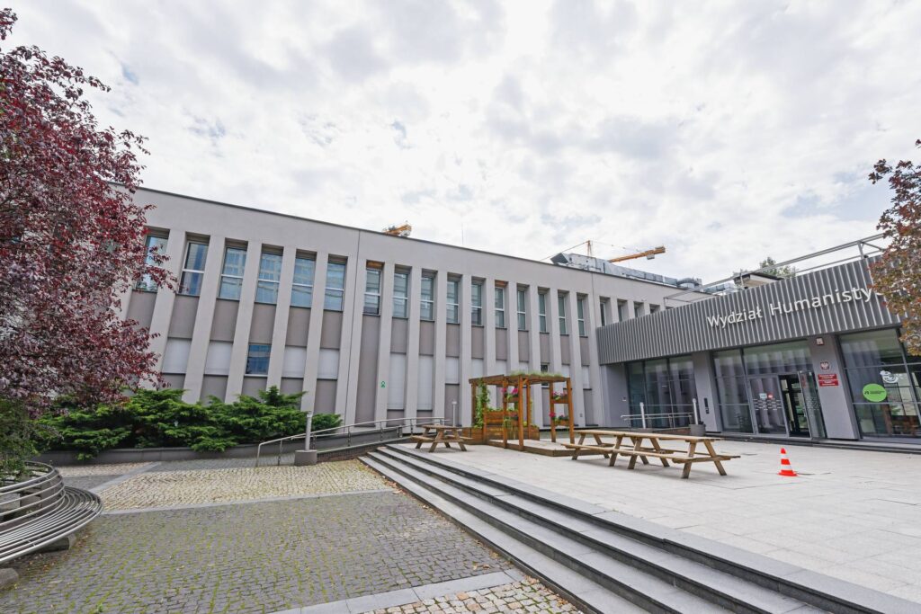 Budynek Wydziału Humanistycznego Uniwersytetu Śląskiego przy ul. Uniwersyteckiej w Katowicach: jasna elewacja z pionowymi podziałami, przeszklone wejście i dziedziniec